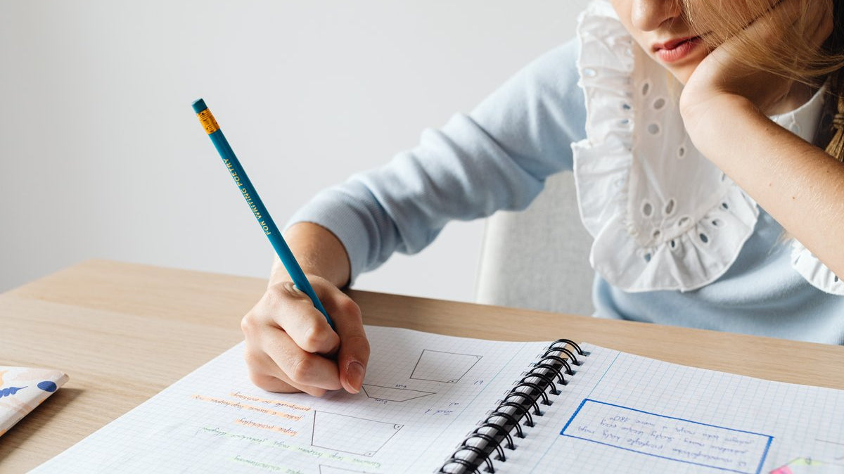 Child resting their chin on one hand while doing homework in a notebook