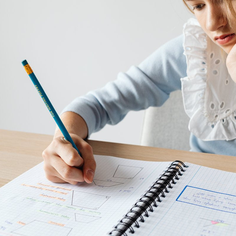 Child resting their chin on one hand while doing homework in a notebook