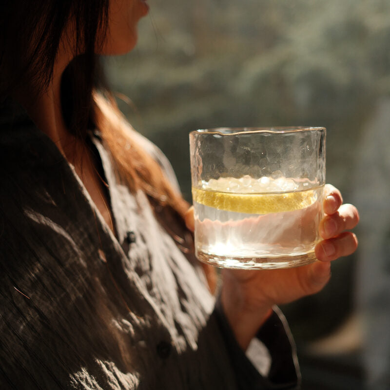 Woman holding a glass of water with lemon as part of a morning wellness routine