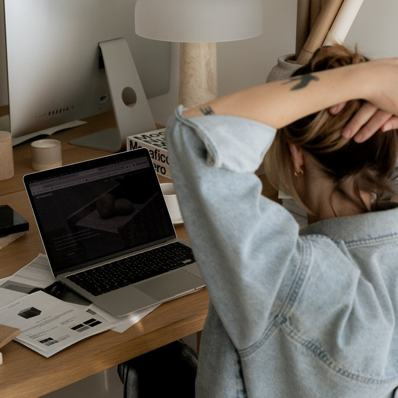 Woman sitting at a desk with her hands clasped behind her head