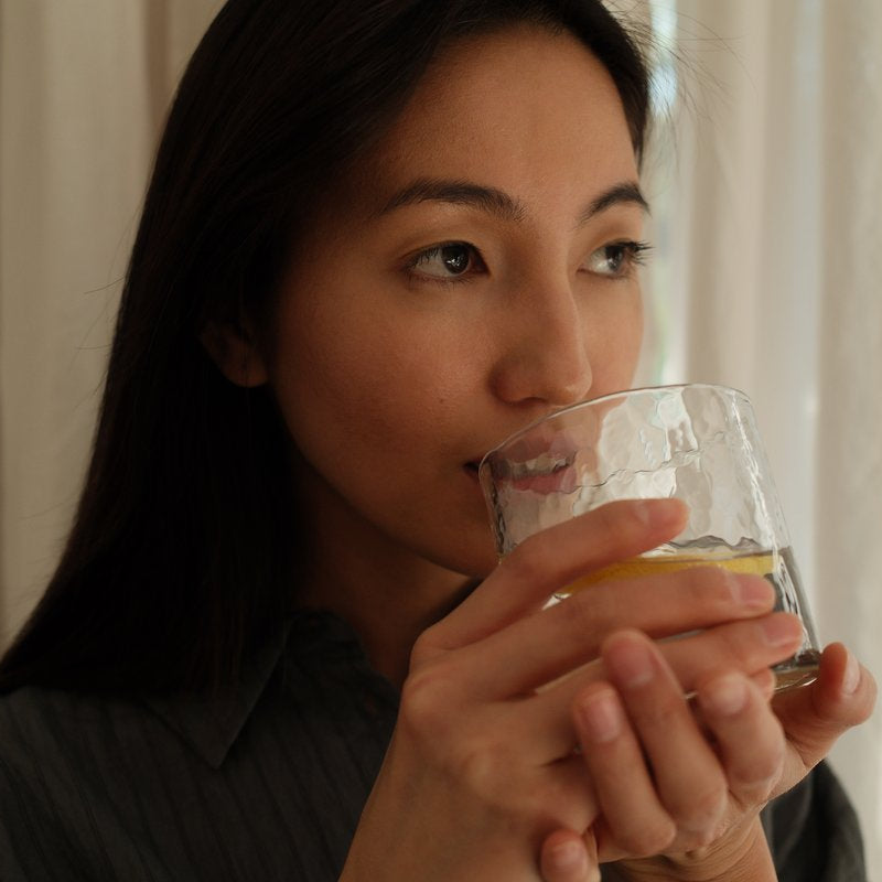 Woman drinking water with lemon from a glass