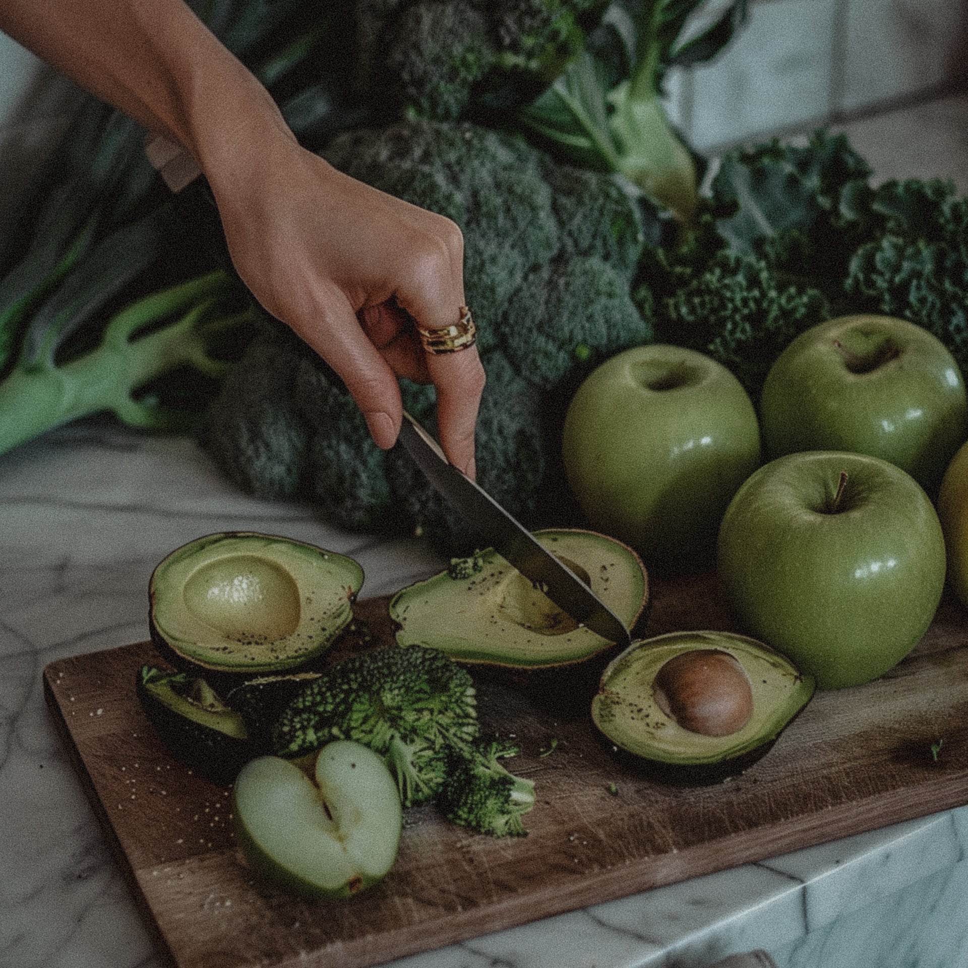 A flat lay of healthy hormone-supporting foods including avocados, leafy greens, seeds, and herbal supplements, styled naturally on a wooden table.