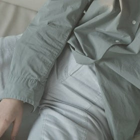 Person wearing a light green jacket and pants in a neutral setting