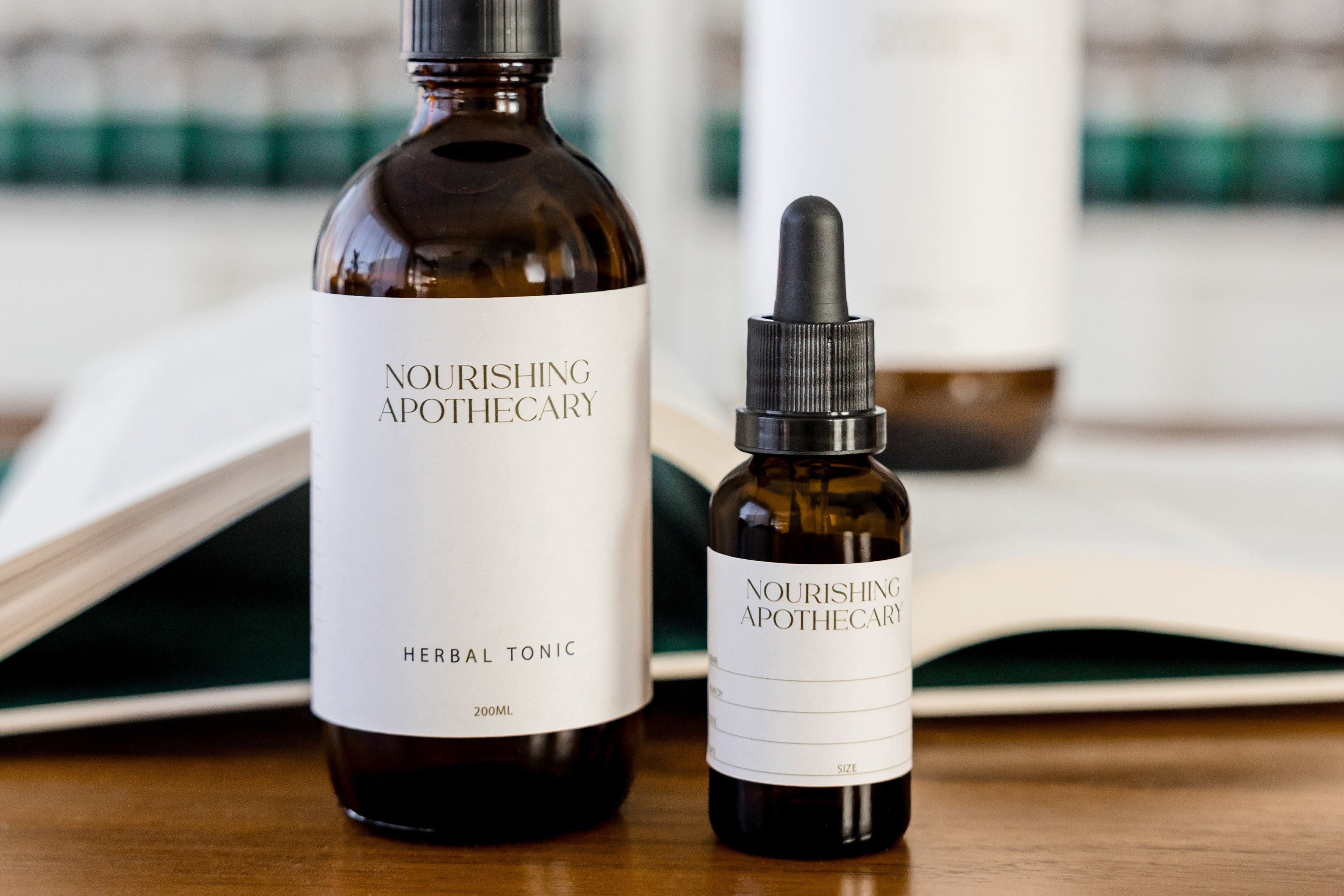 Two bottles of Nourishing Apothecary products on a wooden surface with shelves in the background.