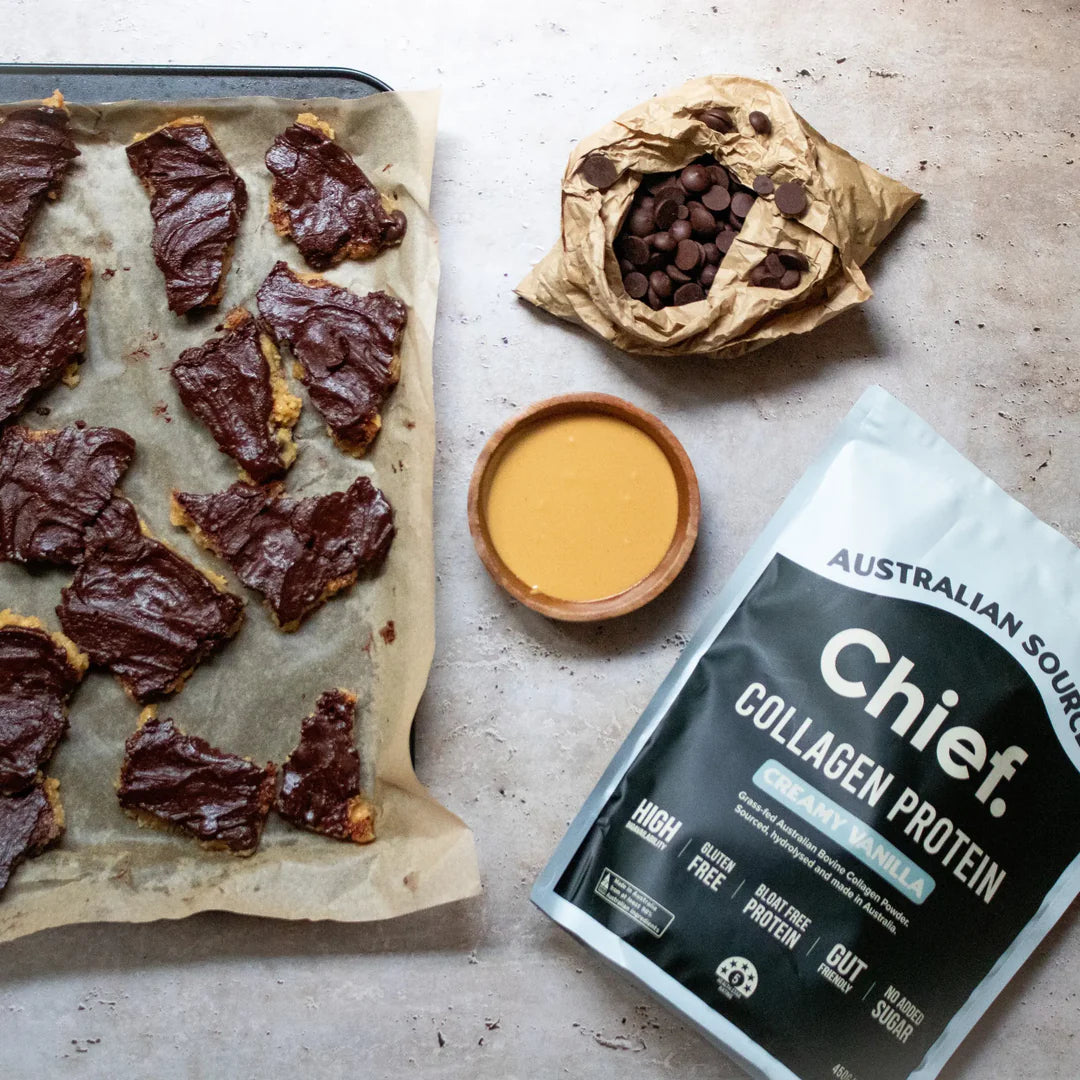 Flat-lay of Chief. Collagen Protein pouch with beef jerky and a drink on parchment paper, showcasing the product as part of a protein-rich snack routine.