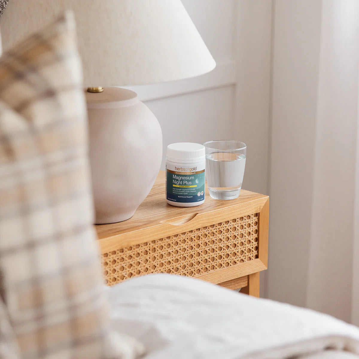 Nightstand with a lamp, glass of water, and supplement container.
