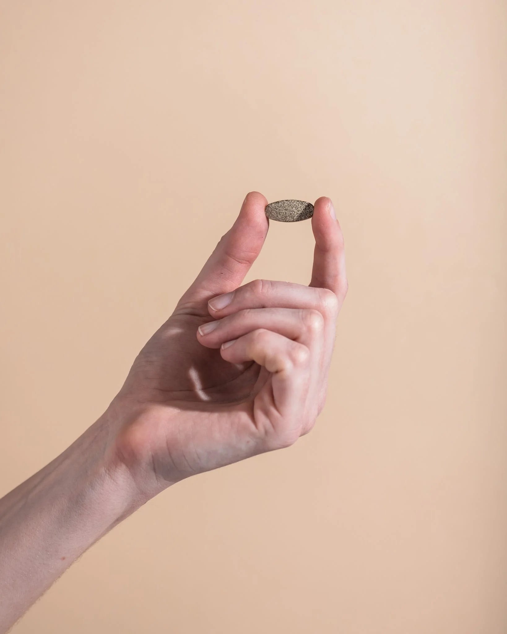 Hand holding a small object against a plain background