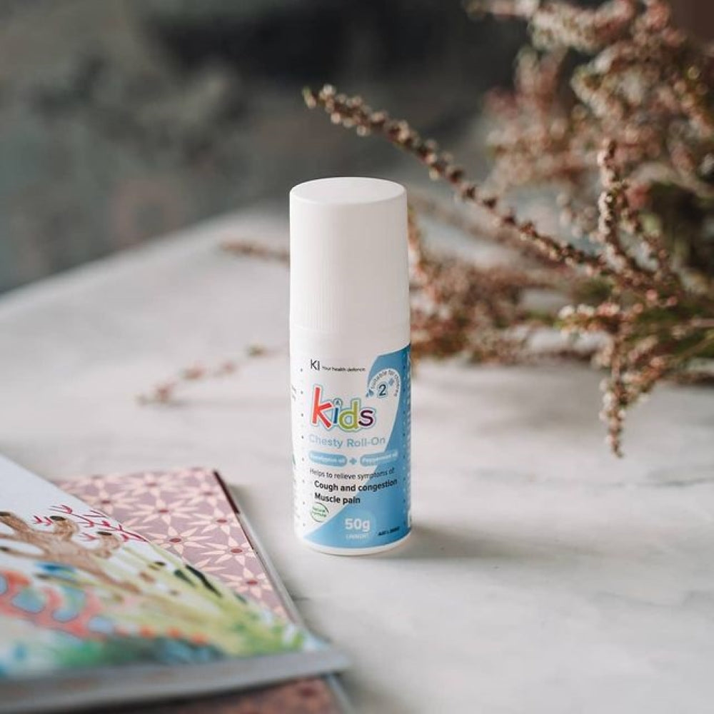 Roll-on bottle for kids on a surface with a magazine and decorative branches in the background