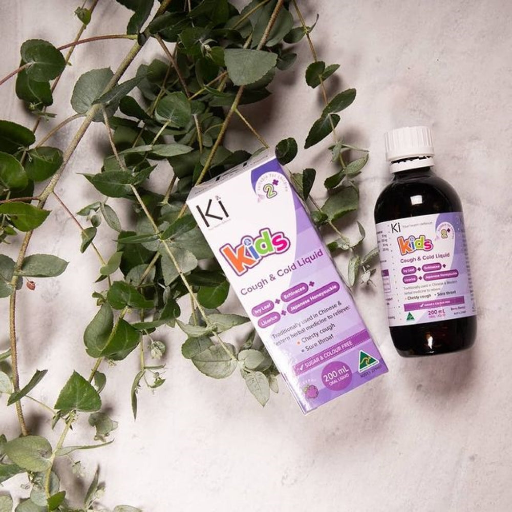 KI Kids Cough & Cold Liquid bottle and packaging on a light background with green leaves.