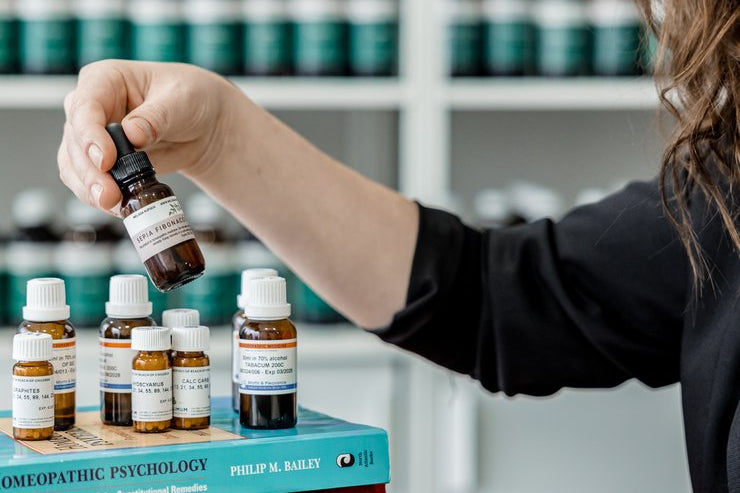 Selecting a homeopathic remedy from a collection beside Homeopathic Psychology and Desktop Companion reference books