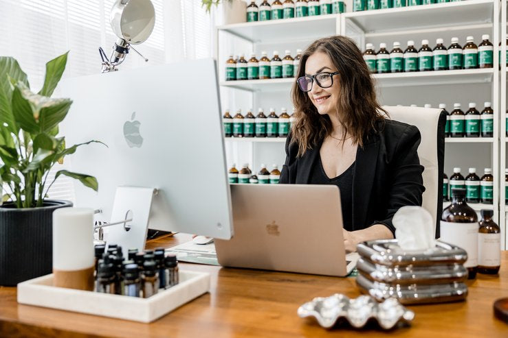Woman working at a desk with a laptop in an office setting.