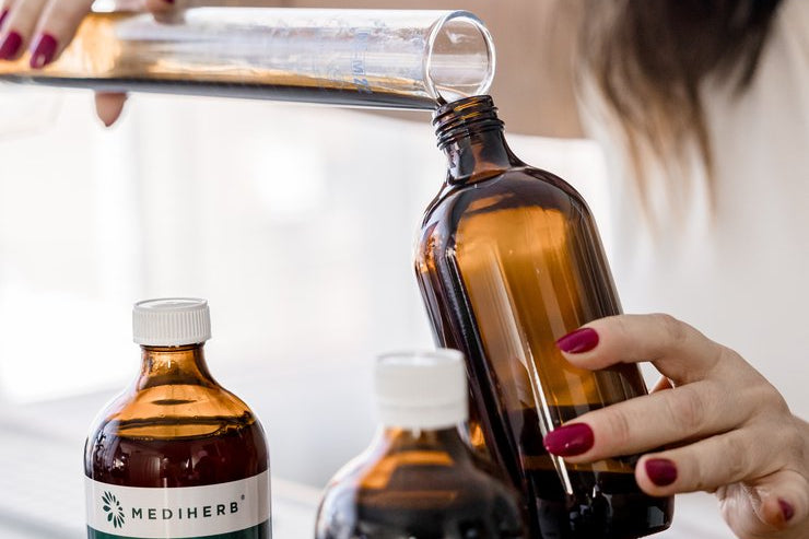 Jaime pouring a herbal extract while compounding medicine in the dispensary