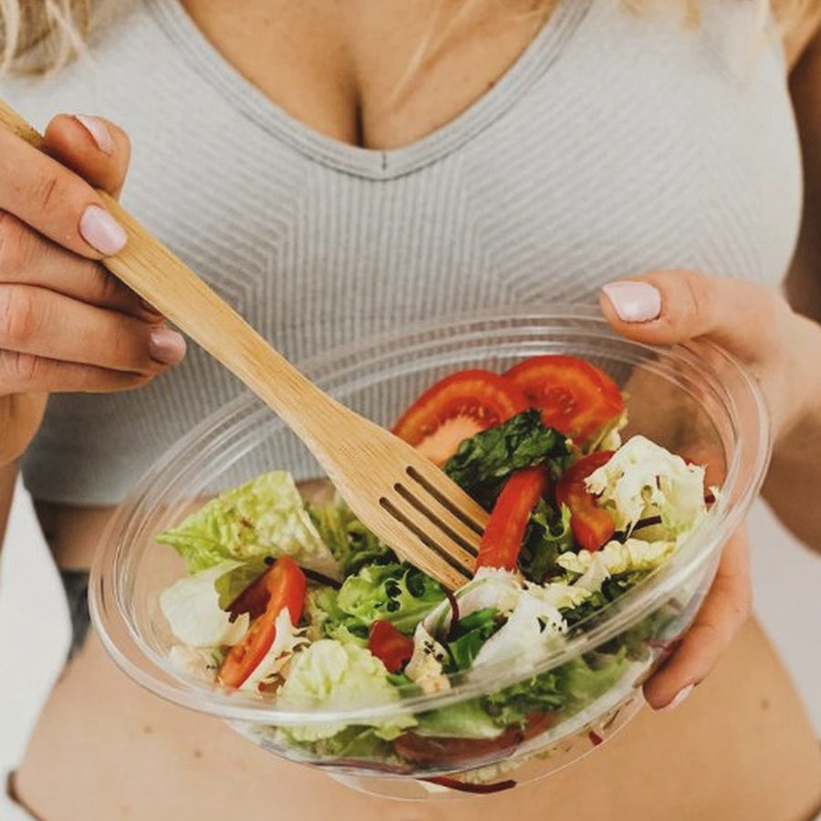 Woman holding a bowl of fresh salad with a wooden fork