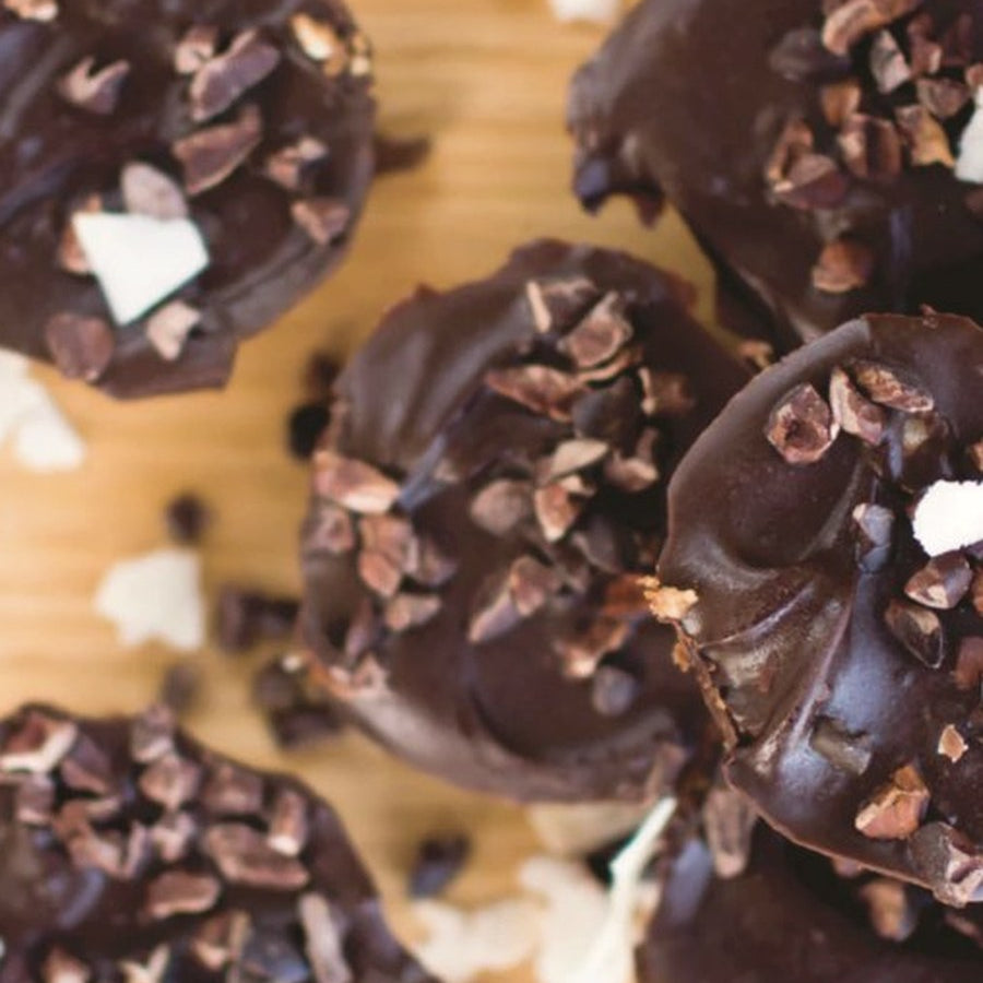 Dark chocolate peanut butter cups topped with cacao nibs on a wooden board