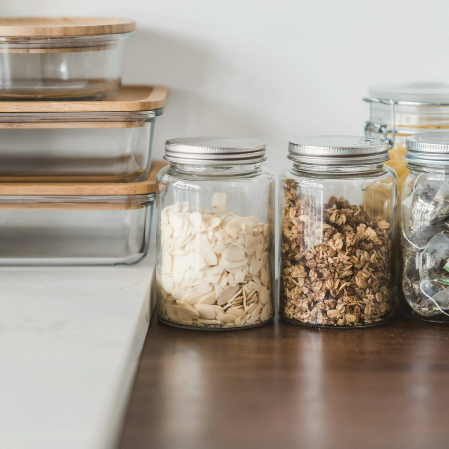 Glass storage jars and bamboo-lidded containers on a kitchen counter
