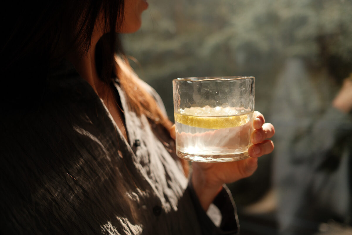 Woman holding a glass of water with lemon as part of a morning wellness routine