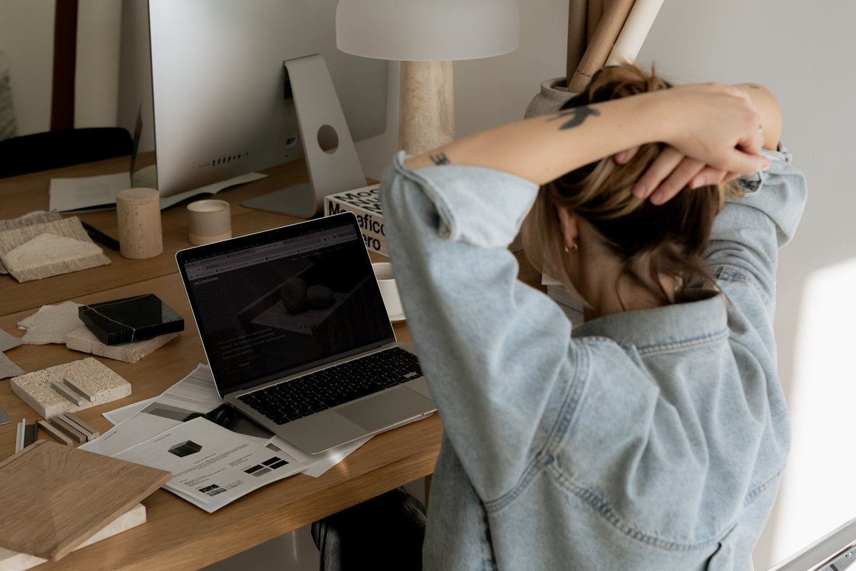 Woman sitting at a desk with her hands clasped behind her head