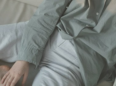 Person wearing a light green jacket and pants in a neutral setting