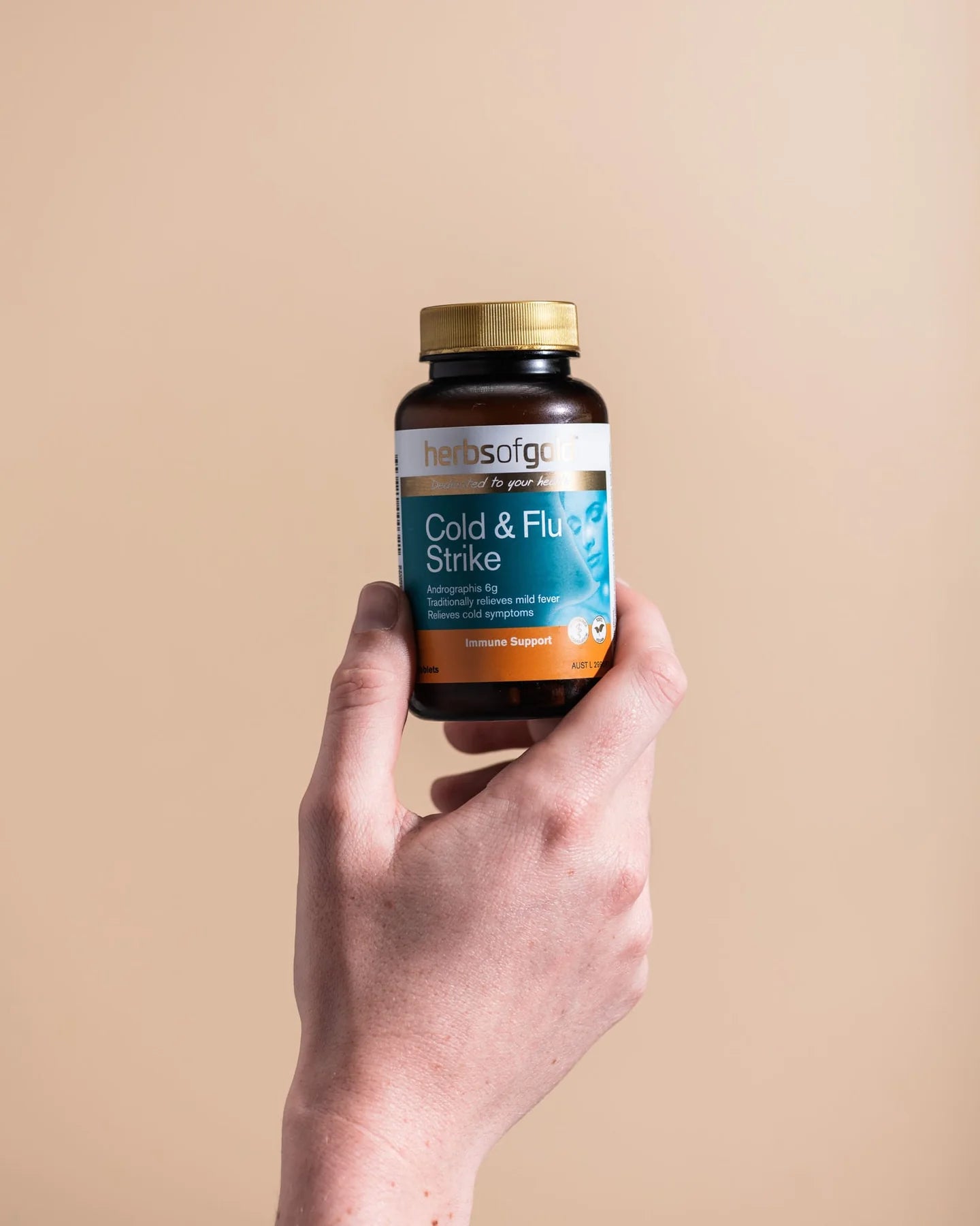Hand holding a bottle of vitamins against a plain background