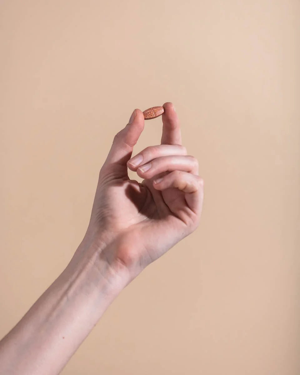 Hand holding a small object against a beige background