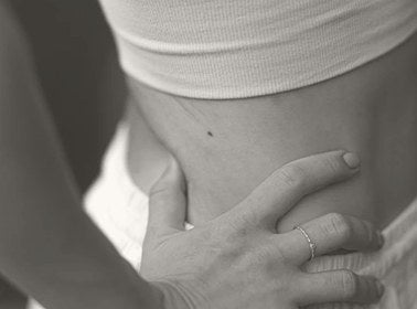 Close-up of a person's hand on their stomach, wearing a ring.