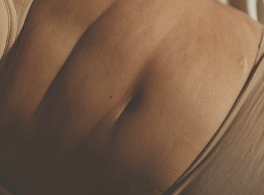 Soft warm-light close-up of skin and natural curves, evoking gentle body awareness
