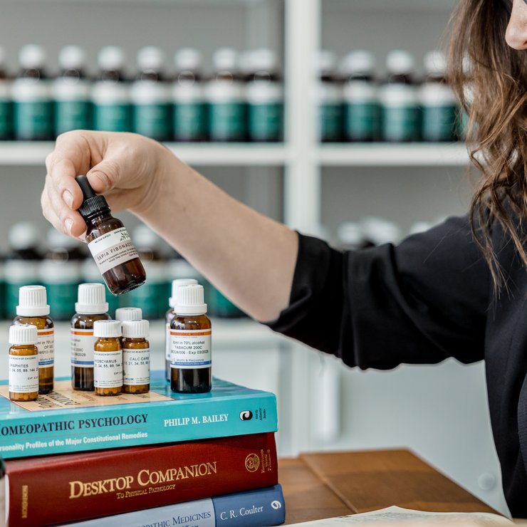Selecting a homeopathic remedy from a collection beside Homeopathic Psychology and Desktop Companion reference books