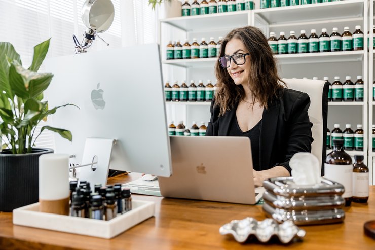 Woman working at a desk with a laptop in an office setting.