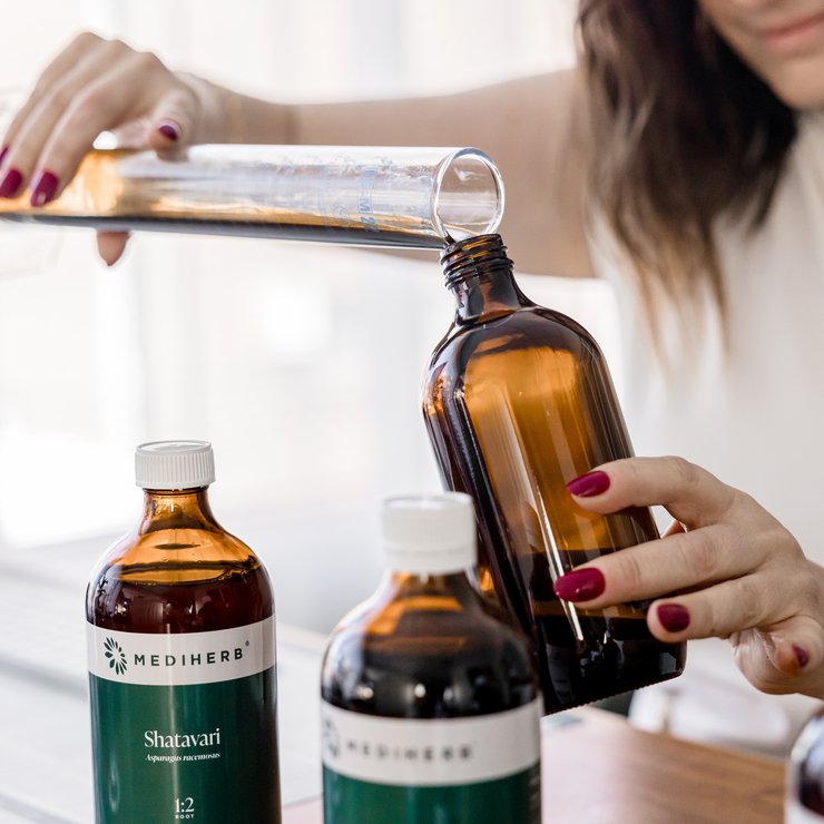 Jaime pouring a herbal extract while compounding medicine in the dispensary