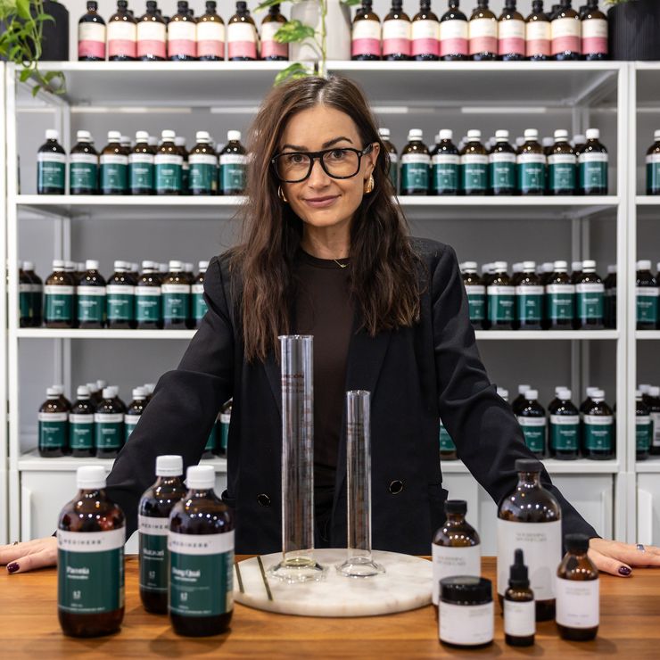 Naturopath Jaime measuring herbal tonics with glass measuring cylinders at the Nourishing Apothecary clinic bench, Liverpool, Sydney.