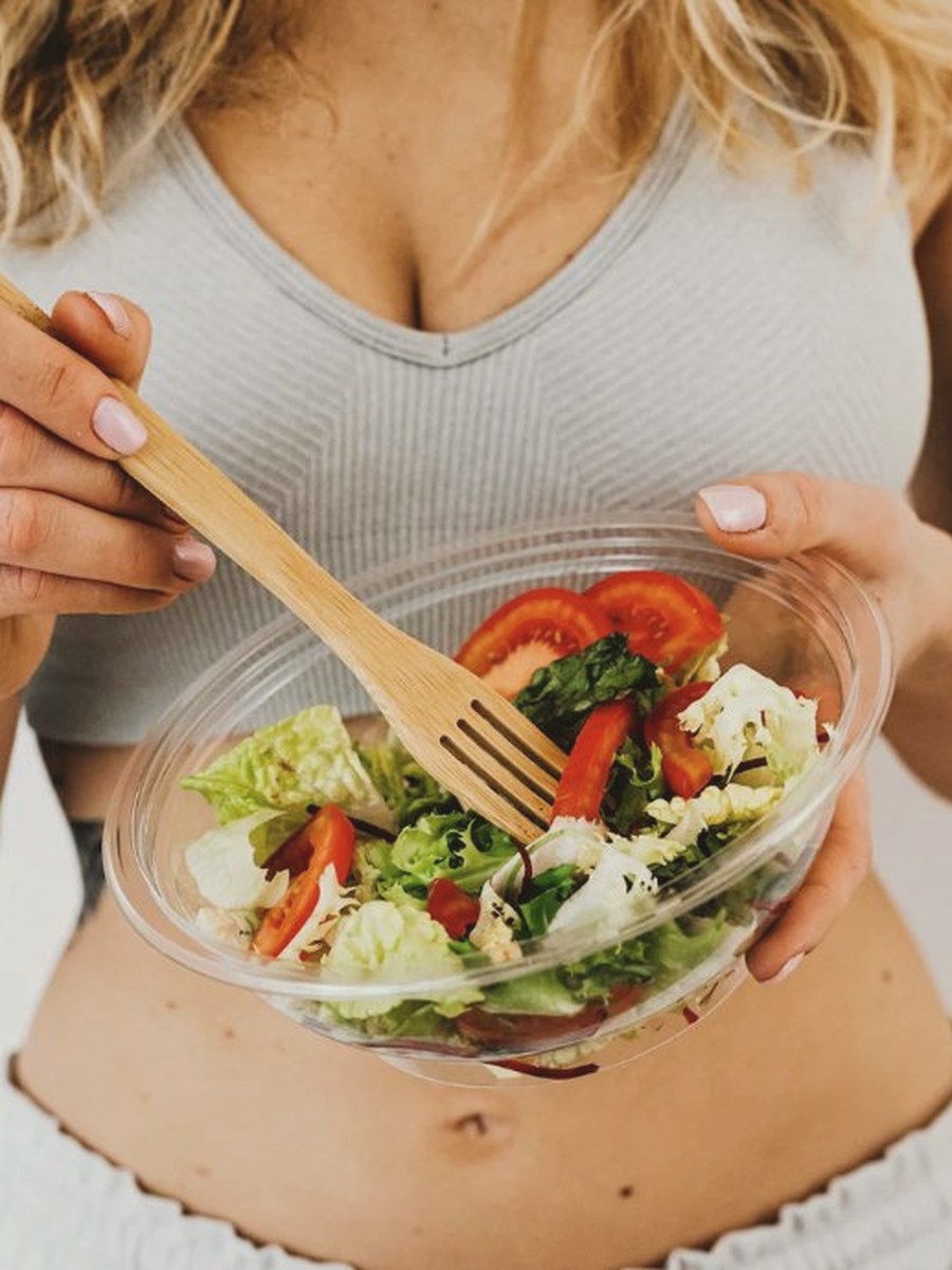 Woman holding a bowl of fresh salad with a wooden fork