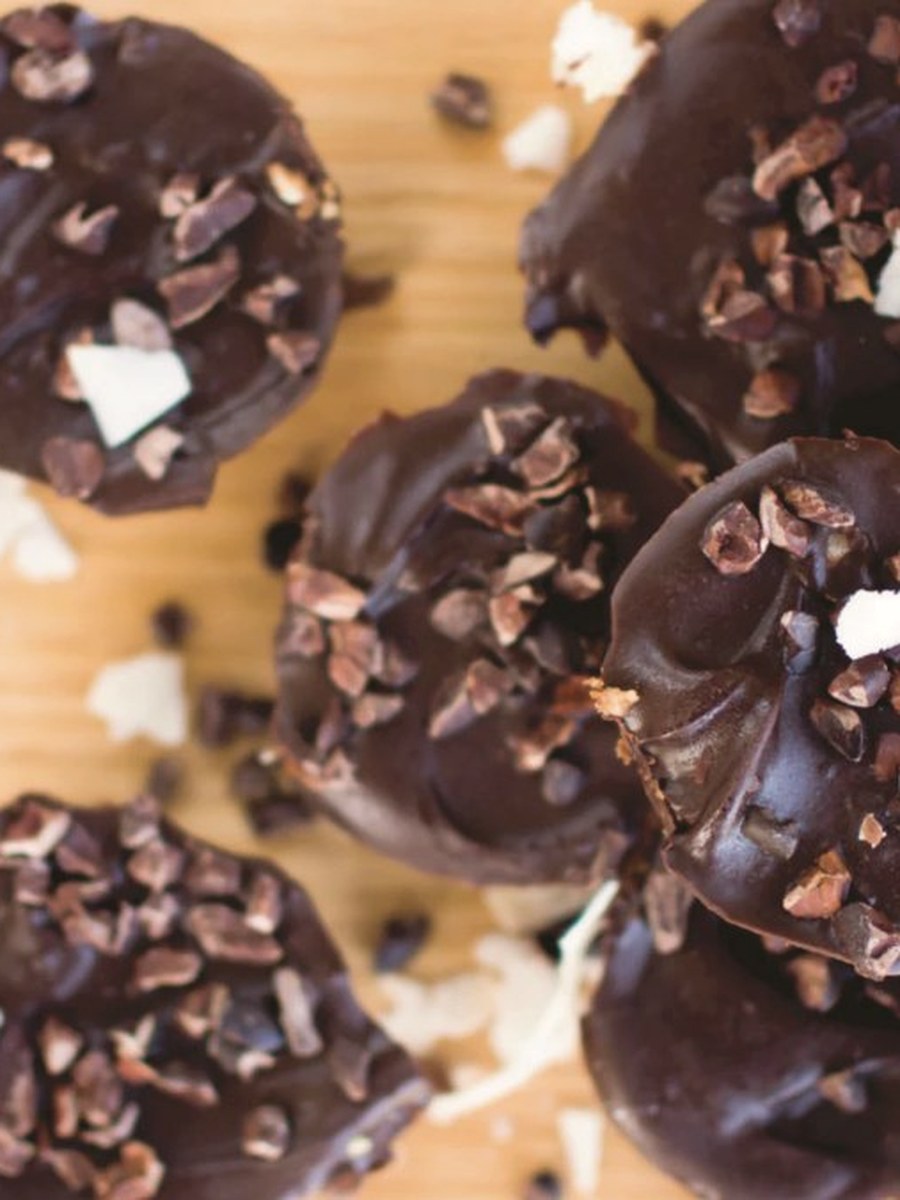 Dark chocolate peanut butter cups topped with cacao nibs on a wooden board