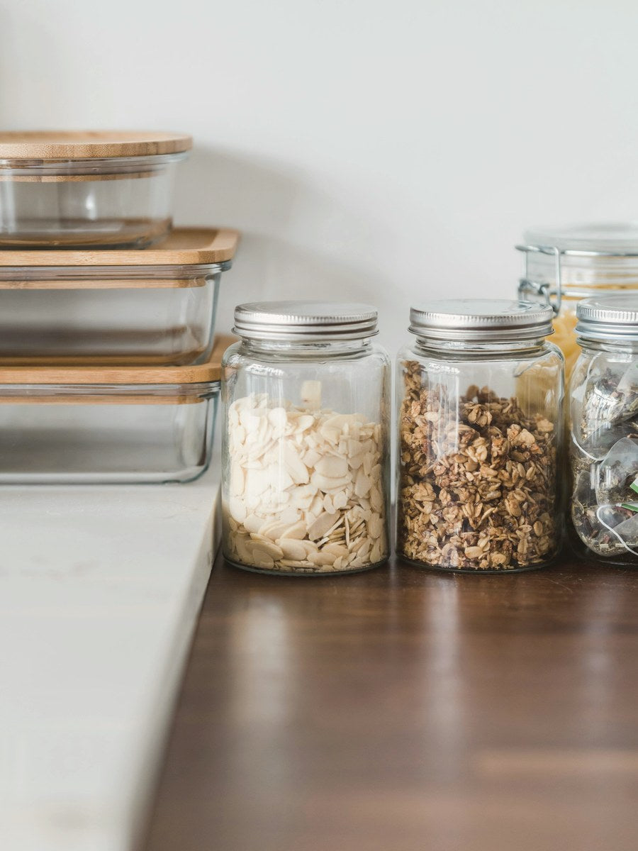 Glass storage jars and bamboo-lidded containers on a kitchen counter