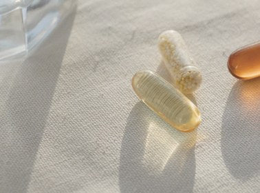 Practitioner-grade supplement capsules resting on natural linen in soft daylight
