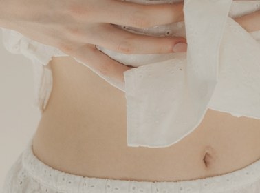 Close-up of a person wearing a white garment with a visible patch on their abdomen.