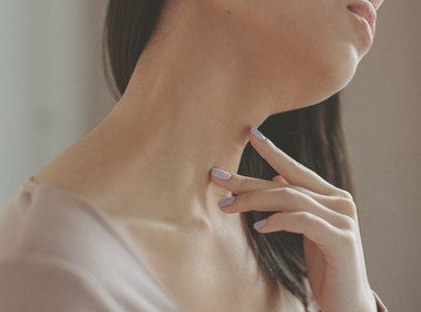 Close-up of a woman's hand resting against her jaw and neck